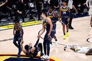 Will Barton #5 and Nikola Jokic #15 of the Denver Nuggets help Jamal Murray #27 off the floor.